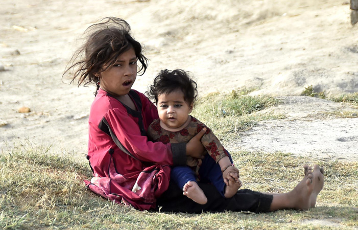 A minor Afghan refugee girl takes care of her younger sibling at Khazana Camp on Charsadda Road. According to the UNHCR spokesperson, more than 700,000 Afghans have returned to their homeland from Pakistan and Iran since the beginning of this year. inp